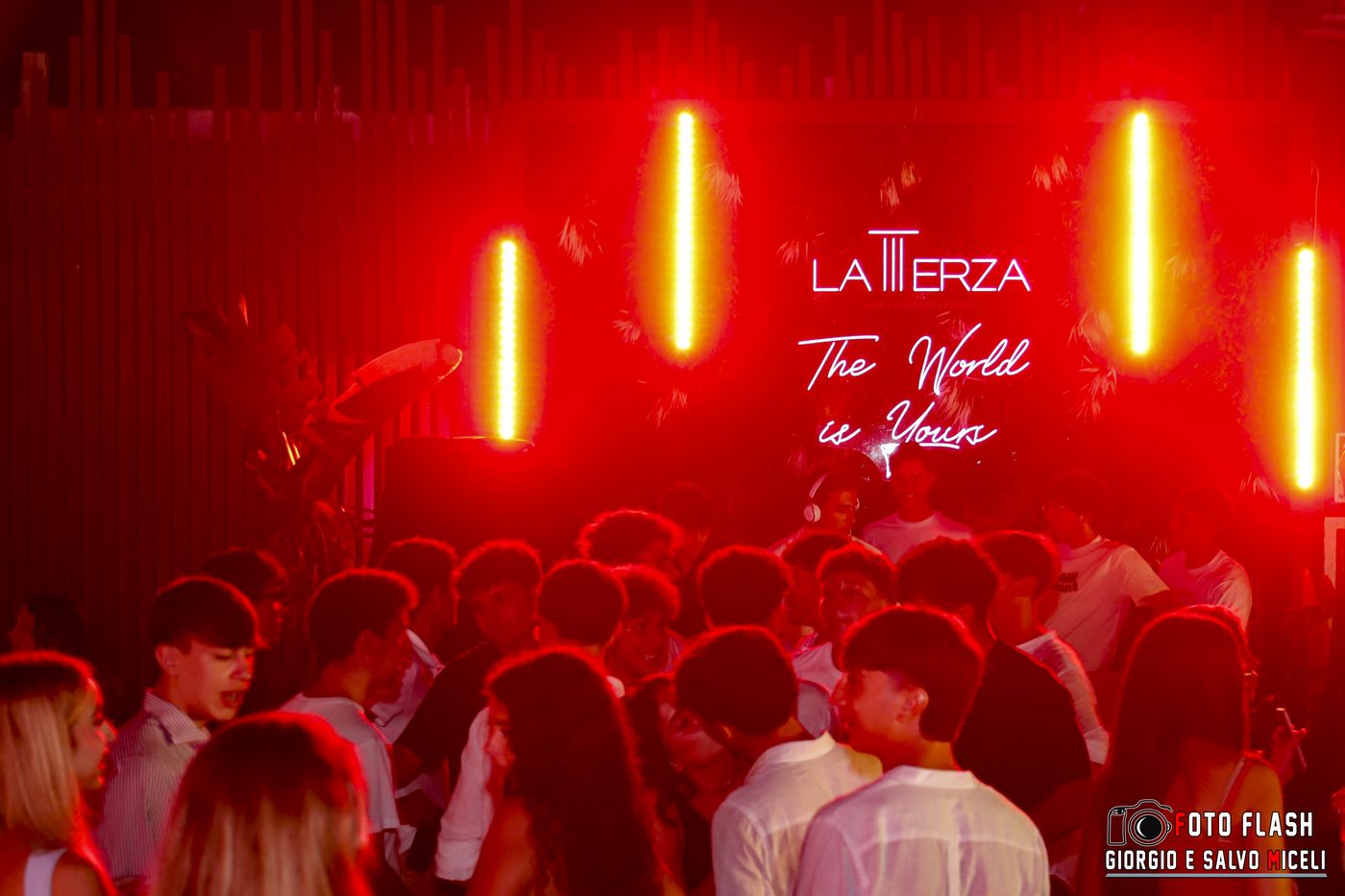 The crowd under deep red light at La Terza in San Leone, Sicily