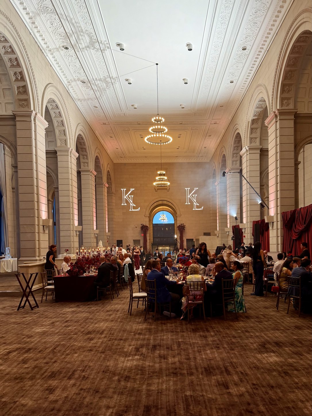 Twin laser-drawn monograms of a couple's initials projected across the stone wall of their reception hall