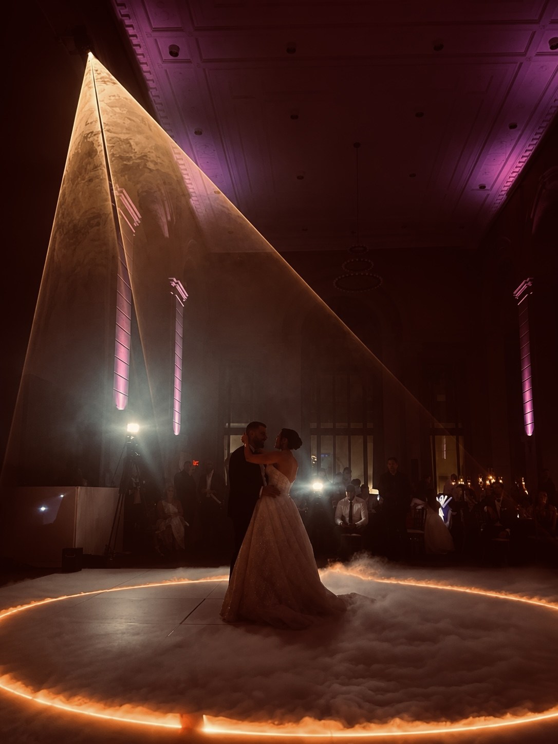 A couple's first dance inside a ring of low-lying fog, a laser fan sweeping the room above them and the columns washed in up-lighting